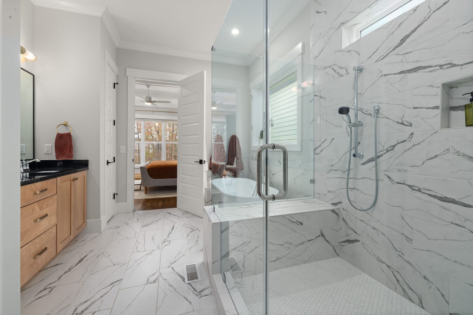 Frameless glass shower door on a white marble walk-in shower with bench seat, installed by Makibaki in the Deerfield area