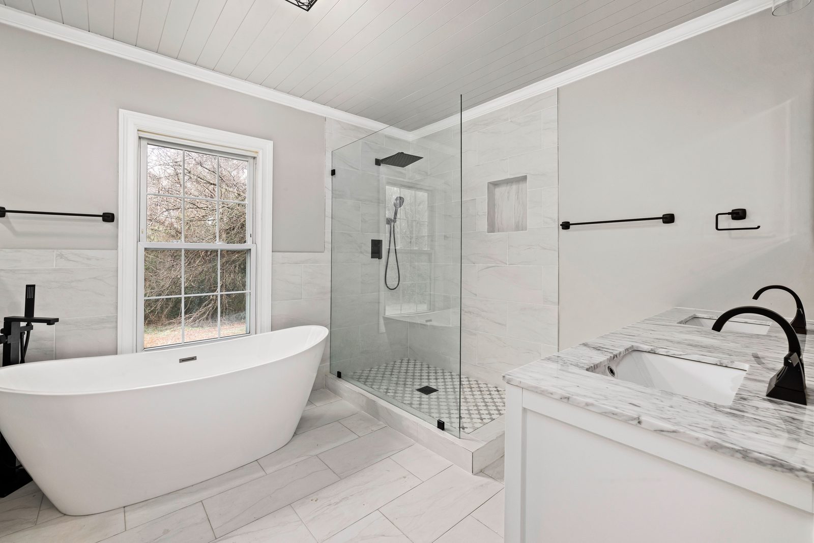 Frameless shower door with black hardware over marble tile
