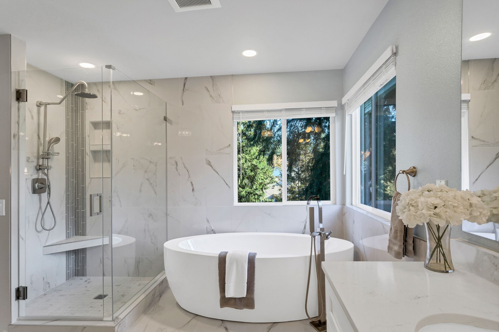 Frameless glass shower and freestanding tub in a bright marble bathroom, installed by Makibaki near Deerfield, IL