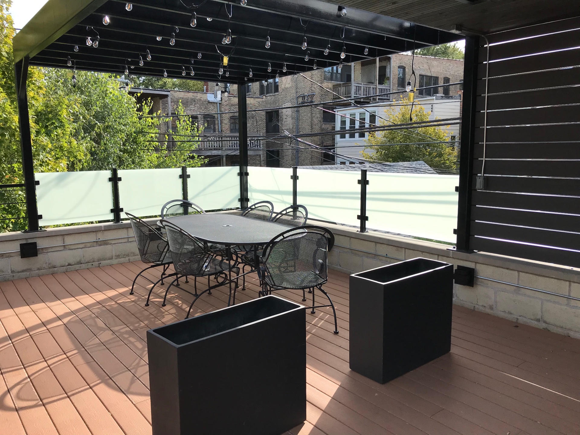 Frosted glass rooftop deck railing with black posts and pergola, installed by Makibaki near Deerfield, IL