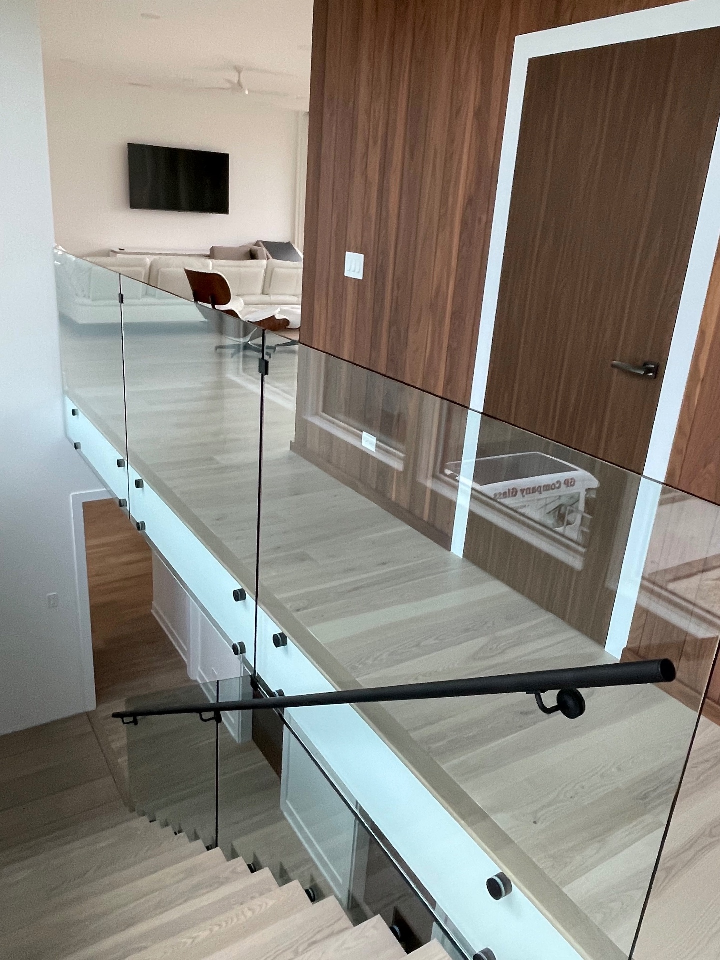 Frameless glass stair railing with matte black handrail in a modern home, installed by Makibaki near Deerfield, IL
